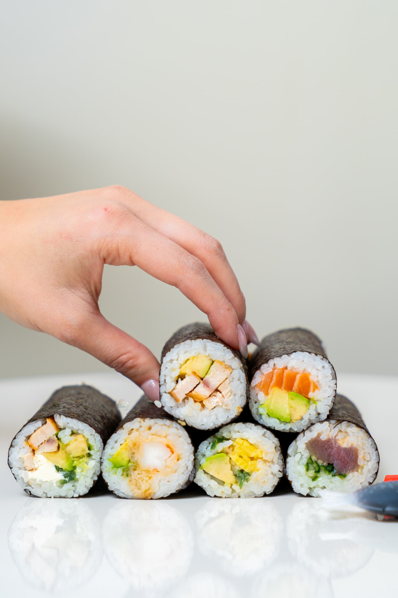 Hand picking a MAKU roll from a stack of fresh rolls